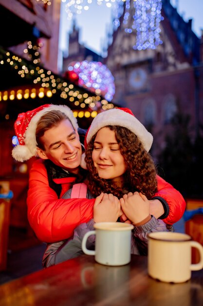 Pareja joven con bebidas en el mercado de Navidad en Wroclaw, Polonia