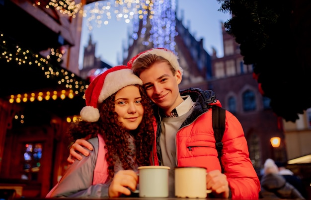 Pareja joven con bebidas en el mercado de Navidad en Wroclaw, Polonia