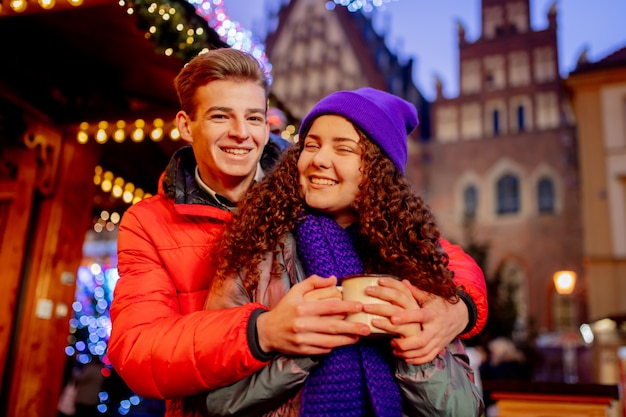 Pareja joven con bebidas en el mercado de Navidad en Wroclaw, Polonia