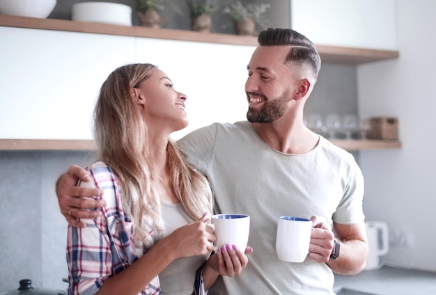 Pareja joven bebiendo café de pie en la cocina