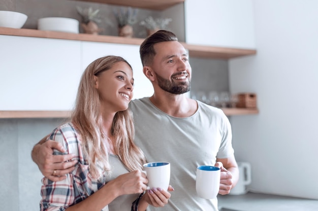 Pareja joven bebiendo café de pie en la cocina