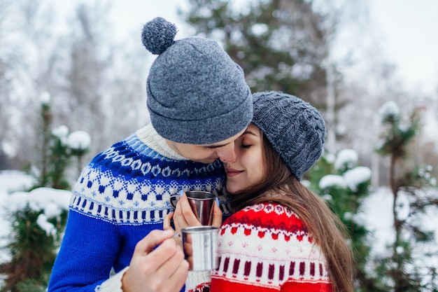 Pareja joven bebiendo té en el bosque de invierno Gente feliz relajándose al aire libre durante las vacaciones Día de San Valentín