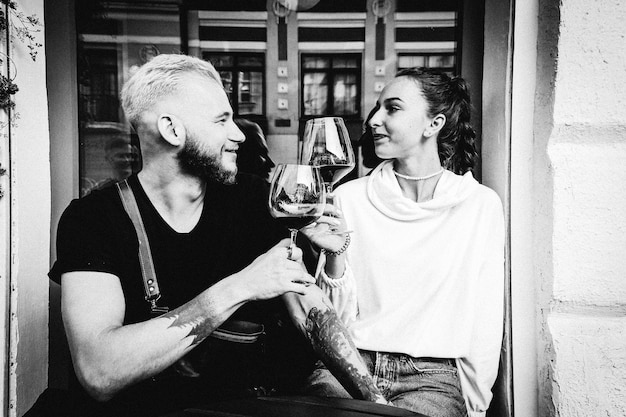 Foto una pareja joven bebiendo vino en la terraza de verano de un café y disfrutando de una cita
