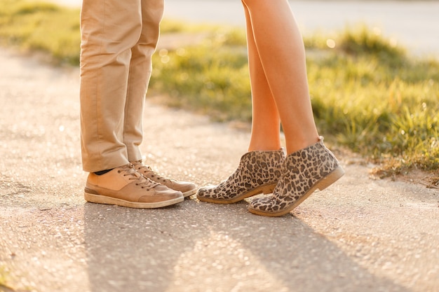 Pareja joven se besa al atardecer. Piernas con zapatos elegantes