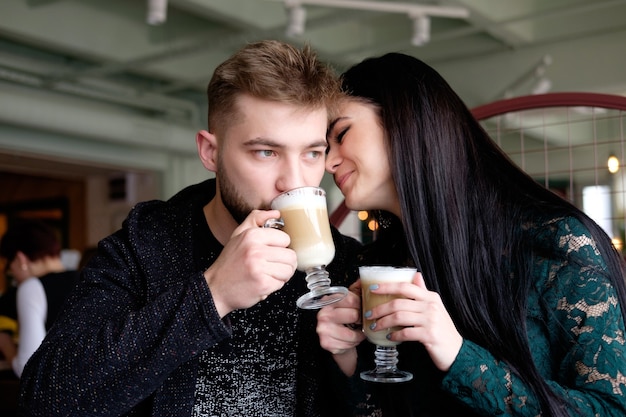 Pareja joven blanca bebiendo capuchino en el café