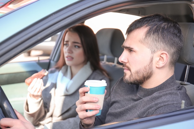 Pareja joven con bocadillo en coche durante el atasco