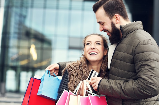 Pareja joven con bolsas de la compra y tarjeta de crédito en la ciudad.