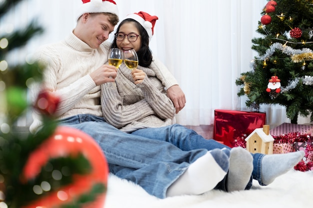 Pareja joven brindando con copas de champán en la celebración de Navidad.