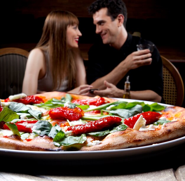 Pareja joven brindando con vino en la pizzería