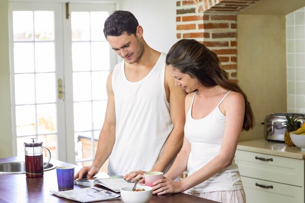 Pareja joven buscando a su organizador personal desayunando en la cocina