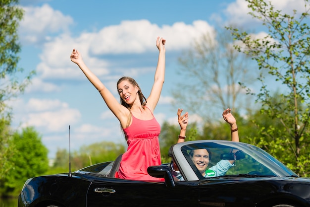 Pareja joven con cabriolet en verano en excursión de un día