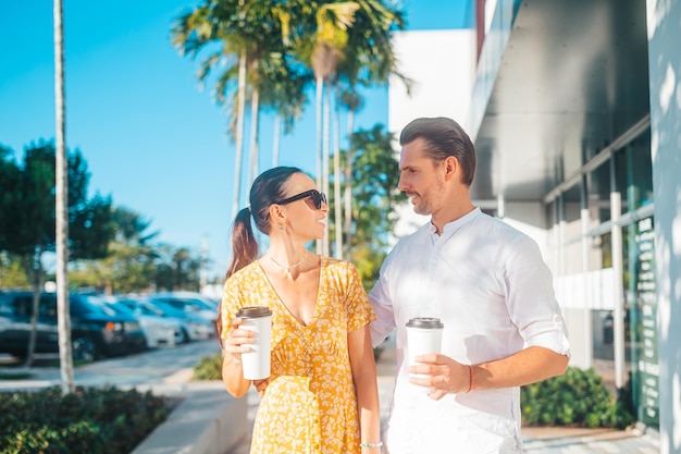 Pareja joven con café para llevar en la calle en la ciudad de verano Adultos jóvenes turistas de viaje en vacaciones de verano