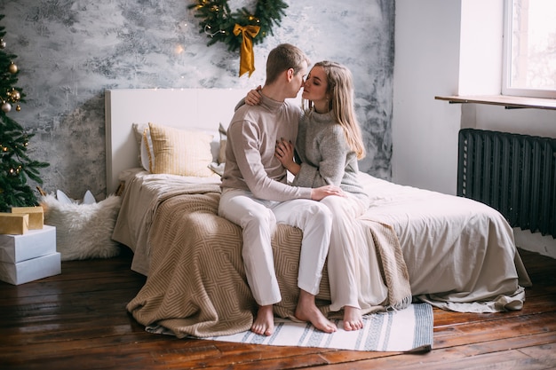 Pareja joven en cama en casa en Navidad