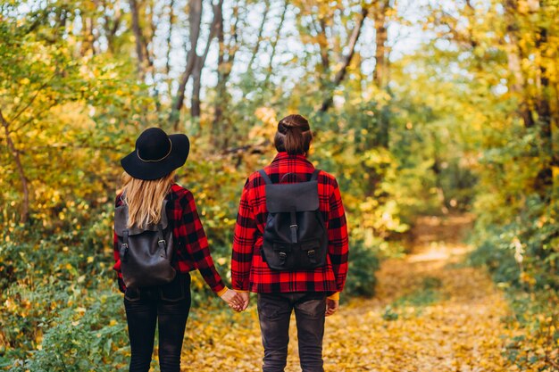 Pareja joven camina por el bosque de otoño tomados de la mano