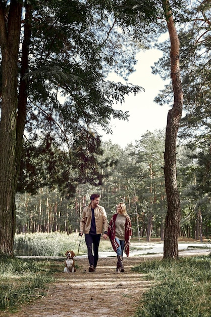 Una pareja joven camina con un perro en el bosque