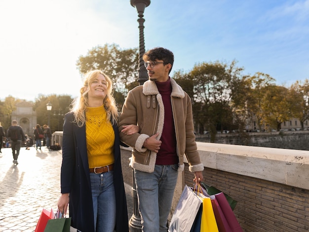 Pareja joven caminando en la ciudad con bolsas de compras tiempo de compras temporada de otoño e invierno