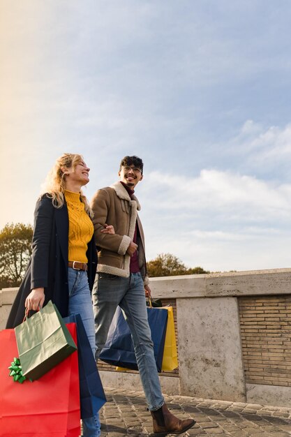 Pareja joven caminando en la ciudad con bolsas de compras tiempo de compras temporada de otoño e invierno