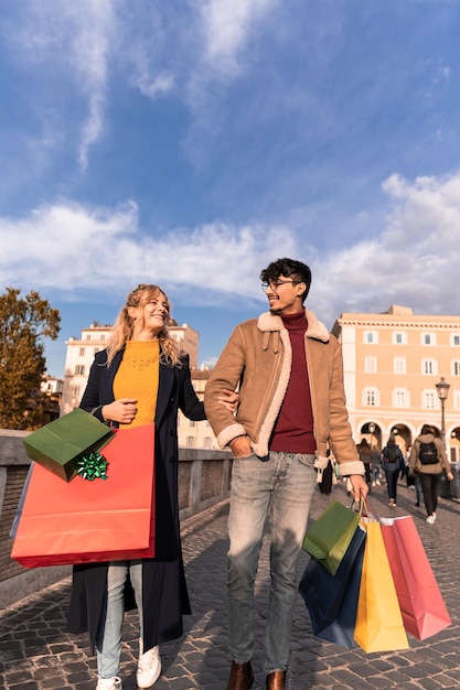 Pareja joven caminando en la ciudad con bolsas de compras tiempo de compras temporada de otoño e invierno