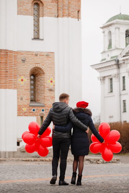 Pareja joven caminando con globos rojos