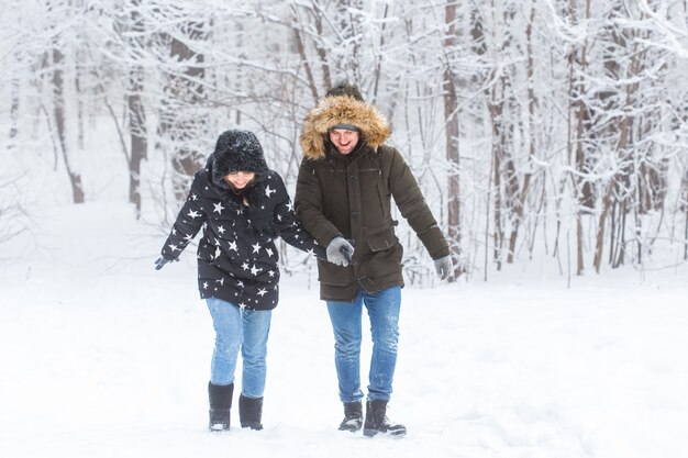 Pareja joven caminando en un parque cubierto de nieve. Temporada de invierno.