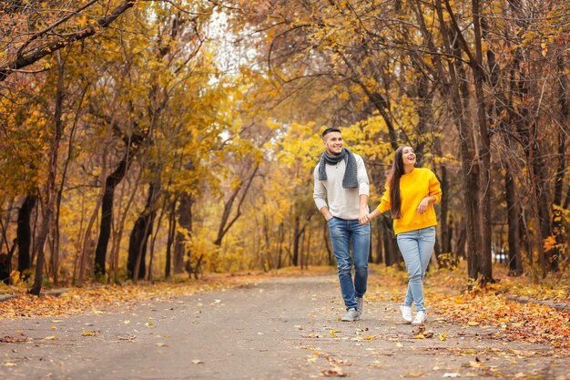 Foto pareja joven caminando en el parque el día de otoño