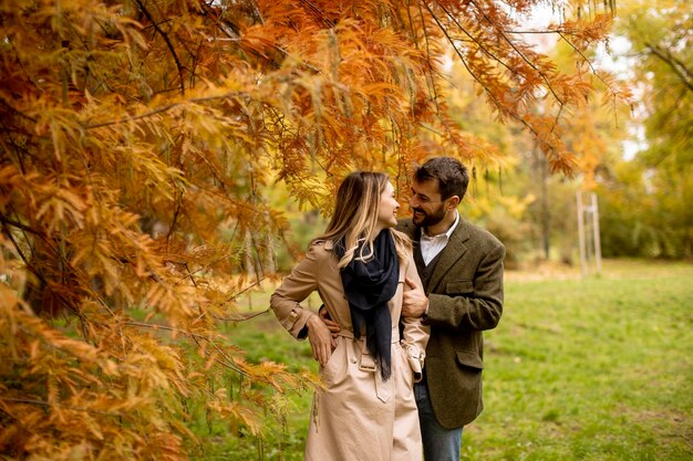 Pareja joven caminando en el parque otoño