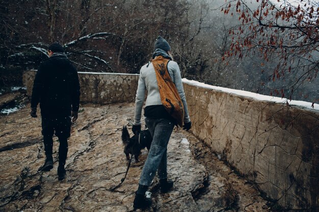 Pareja joven caminando con perro corgi en el parque de invierno.