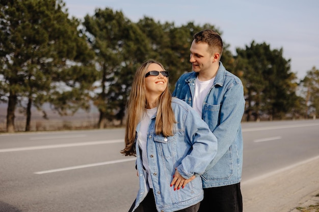 Una pareja joven en el camino con una chaqueta de mezclilla azul y gafas de sol.