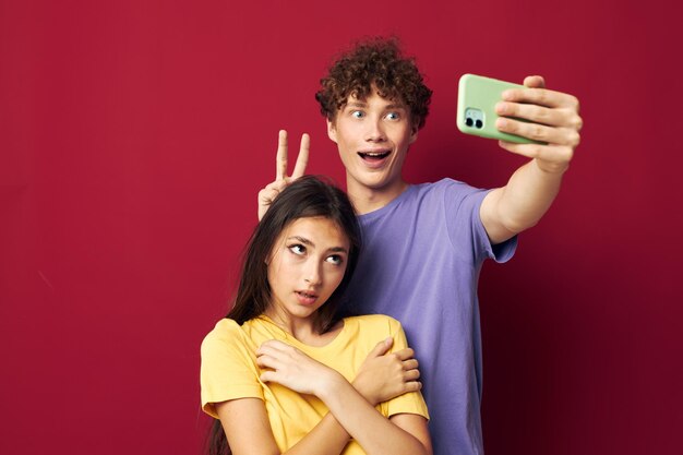 Una pareja joven en camisetas coloridas con un teléfono de fondo aislado