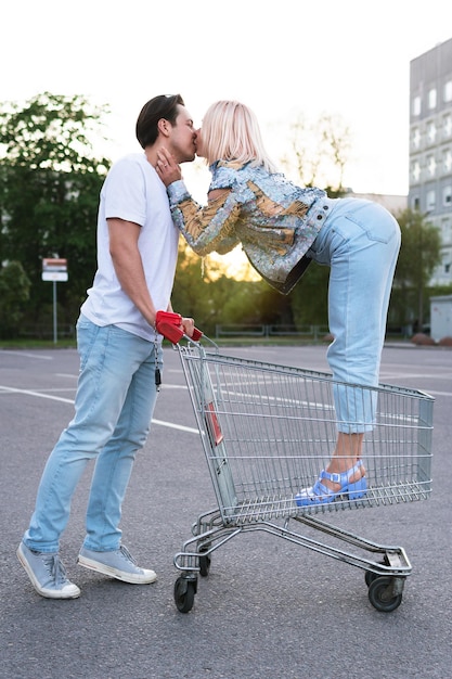 Pareja joven con un carrito de la compra en el estacionamiento del supermercado