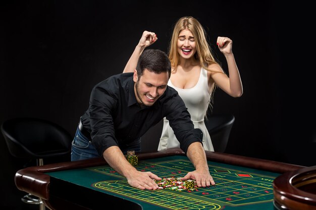 Pareja joven celebrando la victoria en la mesa de la ruleta en el casino