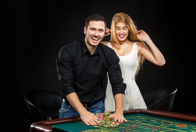 Pareja joven celebrando la victoria en la mesa de la ruleta en el casino