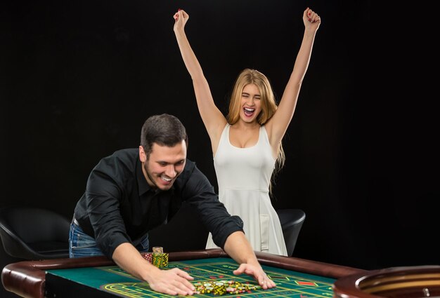 Pareja joven celebrando la victoria en la mesa de la ruleta en el casino