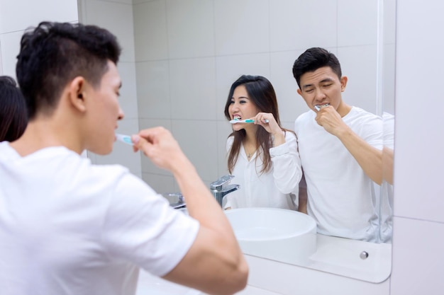 Pareja joven cepillándose los dientes juntos