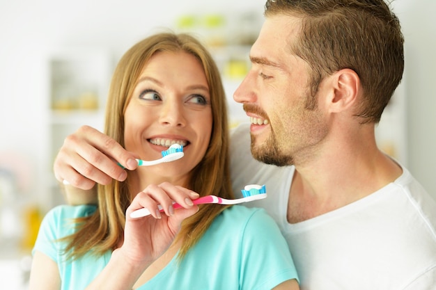 Pareja joven cepillarse los dientes en casa en el baño.