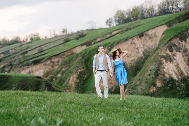 Pareja joven un chico y una chica están caminando en las verdes colinas de la montaña