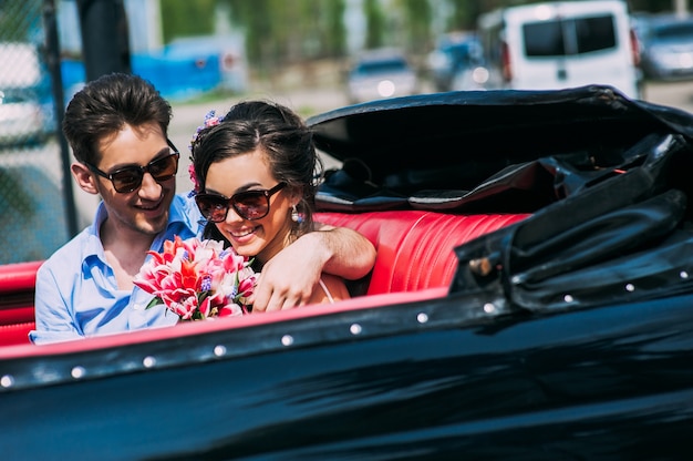 Pareja joven en coches antiguos