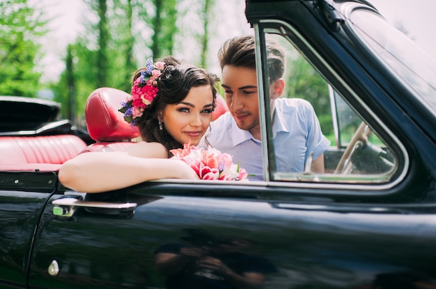 Pareja joven en coches antiguos