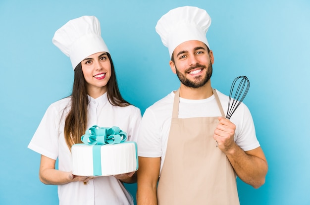 Pareja joven cocinando un pastel juntos tocando la parte posterior de la cabeza