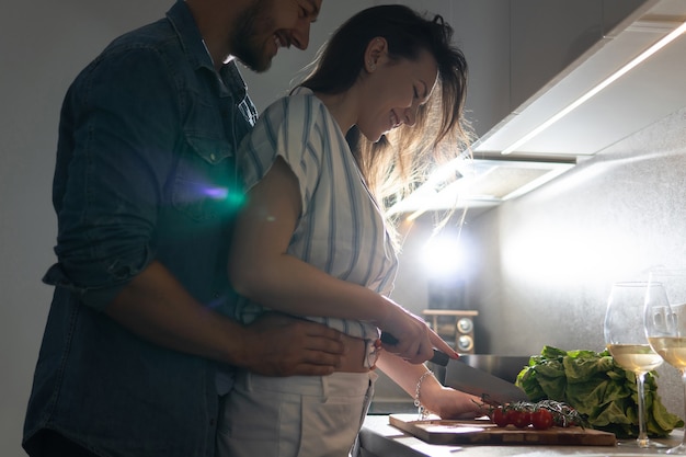 Pareja joven cocinando una sabrosa cena juntos en una cocina por la noche