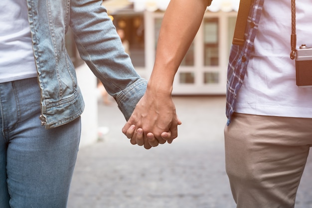 Foto la pareja joven está cogidos de la mano y caminando juntos.