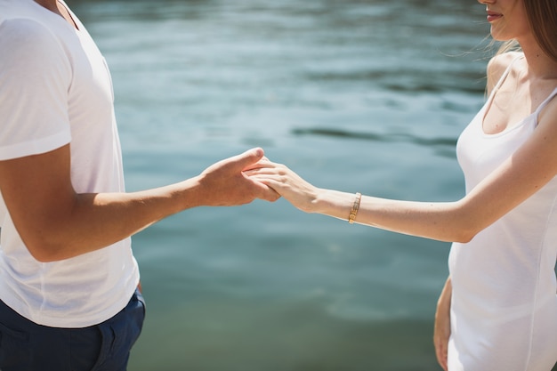 Pareja joven cogidos de la mano en la playa