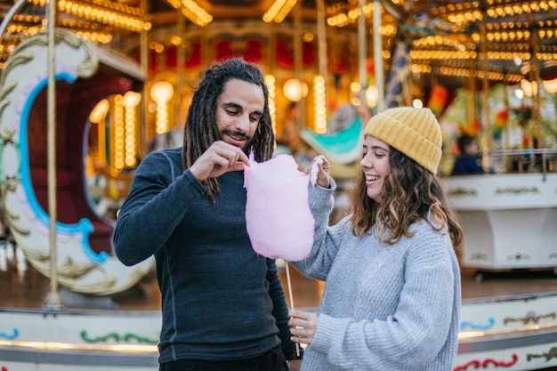 Pareja joven comiendo algodón de azúcar en una feria de Navidad