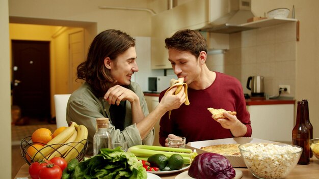 Foto una pareja joven comiendo en la cocina de su casa.