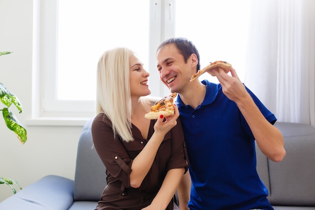 Pareja joven comiendo pizza en casa