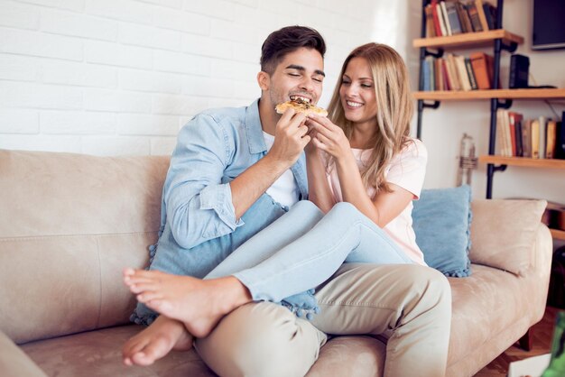 Pareja joven comiendo pizza en casa