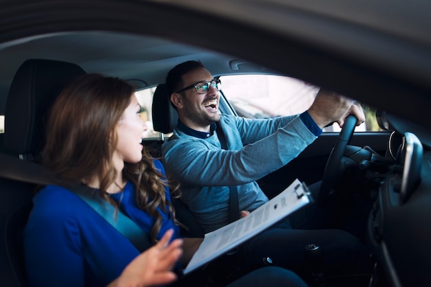 Foto pareja joven comprando un coche nuevo en el concesionario de vehículos.