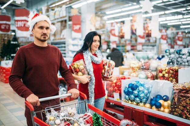 Pareja joven comprando un montón de adornos navideños en el supermercado