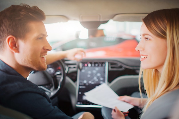 Foto pareja joven comprando su primer auto eléctrico en el showroom