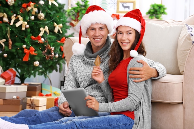 Pareja joven de compras online con tarjeta de crédito en casa para Navidad